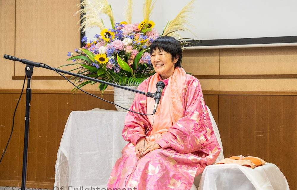 Yogmata speaking at a lecture in Japan
